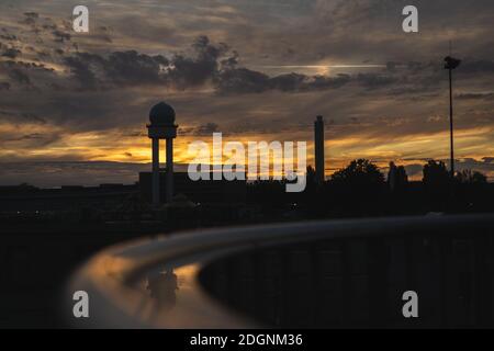Sunset at Berlin Tempelhof Airport. Reflection of flight tower and buildings in metal railing.