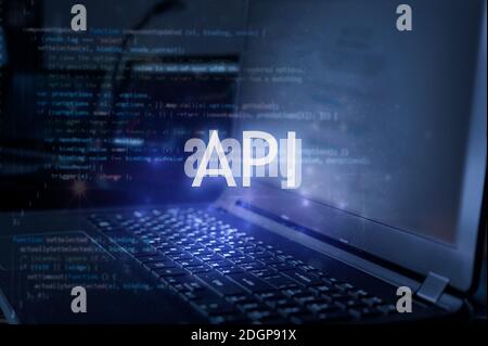 API inscription against laptop and code background. Stock Photo
