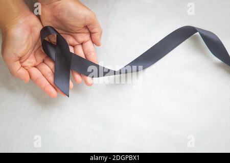 Melanoma awareness ribbon on black color background. Mourning and ...