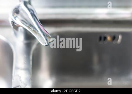 Top view of the mixer lever of a chrome waterfall tap of a domestic kitchen with the aluminum sink in the background. Limestone on the lever Stock Photo