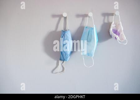 Three different sizes face mask hanging on a white wall Stock Photo