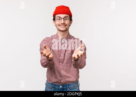 Waist-up portrait pleasant funny young man with beard in red beanie, holding hands as if ready to receive something, get present Stock Photo