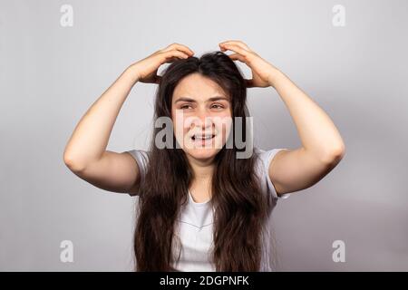 The girl scratches her head and screams. Lice in hair, pediculosis infectious parasitic contagious disease. Stock Photo