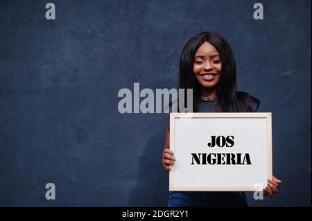 African woman hold white board with Jos Nigeria inscription. Most populous city in Africa concept. Stock Photo