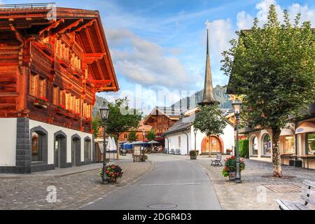 Promenade Gstaad bathing in the golden hour with St. Nicholas Chapel - Gstaad, Switzerland Stock Photo