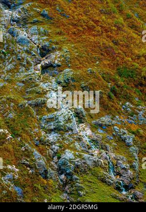 Tall serene waterfall cascading down a steep mountain slope in lush autumn colors.  Stock Photo
