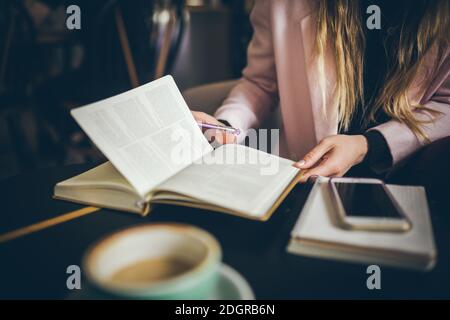 Business, education concept. Woman working in outdoor at coffee shop. Close up caucasian woman hand on wooden table inside cafe