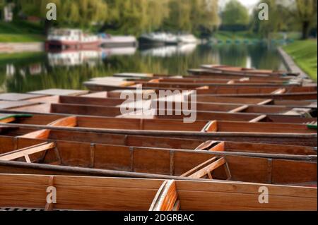 Row of empty Punts moored on the River Cam at Cambridge with defucused boats in the background