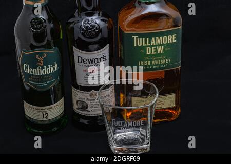 KYIV, UKRAINE - AUGUST 17, 2019: Bottles of Glenfiddich, Dewars and Tullamore DEW Scotch and Irish single malt and blended whisky against black backgr Stock Photo