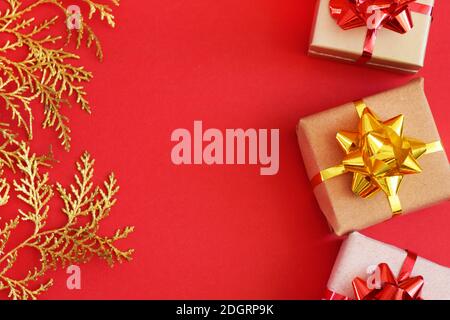 DIY handmade Christmas gift boxes in craft paper. Boxes on a red background and golden sprigs on a red background. Copy spase Stock Photo