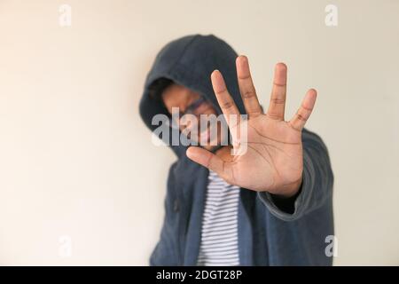 young man in hood show stop sigh against a wall  Stock Photo