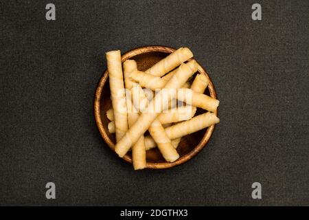 Wafer rolls in a wooden bowl and on a dark background Stock Photo