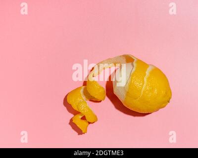 Lemon and spiral peel on pink background hard light Stock Photo