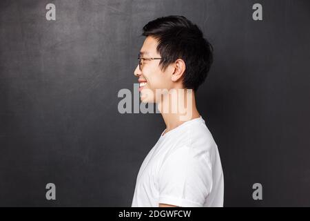 Profile portrait of happy smiling asian man in white t-shirt looking at left blank space, grinning friendly away as posing again Stock Photo