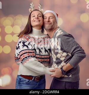 Middle-aged happy couple holding a paper concept mistletoe and looking very loved celebrating for christmas Stock Photo