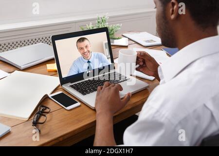 Businessman At Laptop Having Online Meeting With Coworker At Workplace Stock Photo