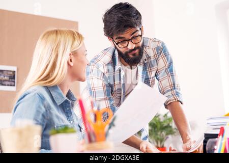 Two young beautiful focused business people in the office discussing project notes. Stock Photo