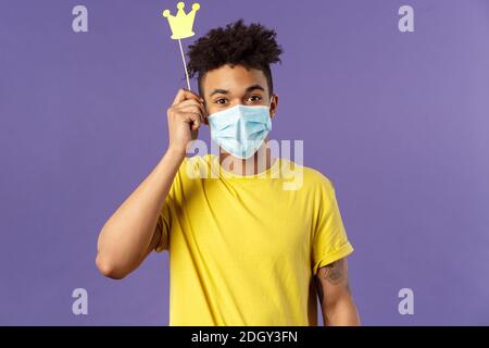 Social-distancing, coronavirus, health concept. Portrait of upbeat, happy hispanic man in medical face mask, holding small paper Stock Photo