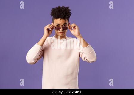 Portrait of sassy and confident young judgemental man, taking-off glasses squinting suspicious, security checking out and judgin Stock Photo