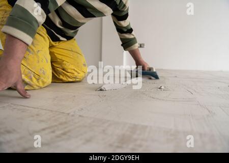 Tilers filling the space between ceramic wood effect tiles Stock Photo