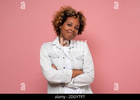 African american millennial woman smiling at camera. Studio shot on pink wall. Stock Photo