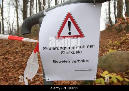 09 December 2020, Mecklenburg-Western Pomerania, Sellin: A sign with the inscription 'Sicherungsmaßnahmen Steilküste' (safety measures for steep coast) hangs on a railing. On the steep coast of Sellin on the island of Rügen two excavators are busy demolishing an old NVA bunker on the same day. The 300 square metre GDR bunker, made of one metre wide concrete walls, had been built in 1959. Until 1988 it had been part of the Technical Brigade Coast on the island of Rügen and was part of the radio and airspace surveillance in the Baltic Sea area. The cost of the demolition work is currently estima Stock Photo