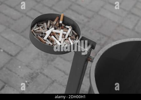 A lot of different cigarette butts in the metal ashtray outdoor. Stock Photo