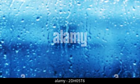 A blurry image of a window pane with raindrops running down it. Bad weather. Background. Stock Photo