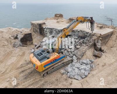 Sellin, Germany. 09th Dec, 2020. At the steep coast of Sellin on Rügen an excavator is busy demolishing an old NVA bunker (aerial view with a drone). The 300 square metre GDR bunker made of one metre wide concrete walls had been built in 1959. Until 1988, it was part of the Technical Brigade Coast on the island of Rügen and was part of the radio and airspace surveillance in the Baltic Sea area. The cost of the demolition work is currently estimated at around 120 000 euros. Credit: Stefan Sauer/dpa-Zentralbild/dpa/Alamy Live News Stock Photo