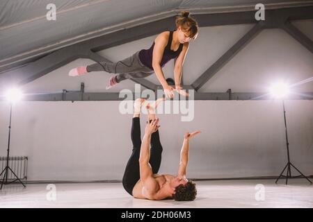 Young couple Couple practicing acro yoga in gym. Healthy lifestyle. Acroyoga. Couple yoga. Partner yoga. Muscular man throwing w Stock Photo