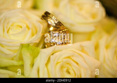 Wedding rings on white roses background Stock Photo