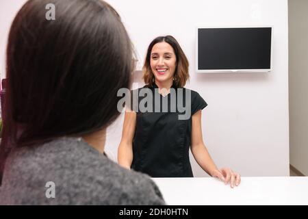 dependent and client talking very happily before paying for treatment in a body care clinic Stock Photo