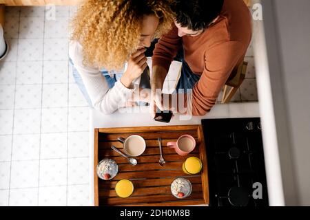 Stock photo of an unrecognizable middle aged woman and man standing in a kitchen and laughing. They are having a conversation. Stock Photo