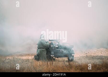 Re-enactor Dressed As World War II German Soldier Open Fire Near Motorcycle. Historical Reenactment Stock Photo