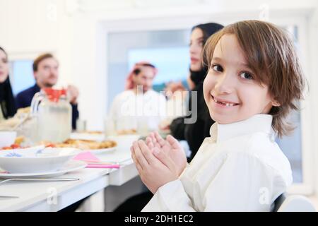 Little muslim boy praying with family before iftar dinner Stock Photo