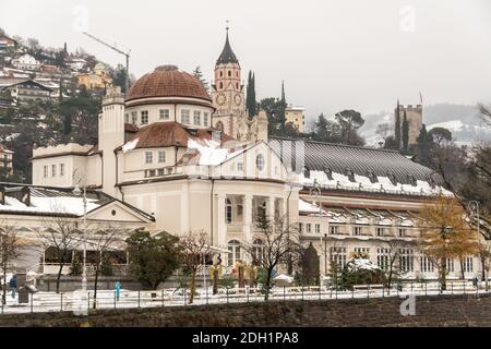 Kursaal oder Kurhaus on passeggiate (promenade) with duomo bell tower and Pulverturm (Torre Polveriera - Tower of powder) with snow in winter - Merano Stock Photo