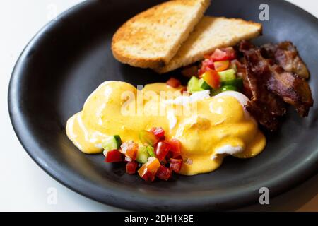 Eggs Benedict - bread ,becon and tomato, poached eggs, and delicious buttery hollandaise sauce Stock Photo