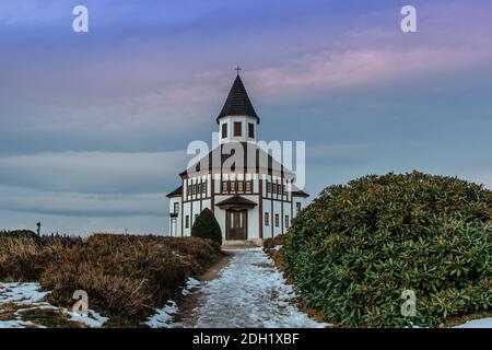 Small white rural Tesarovska chapel with cemetery in the village of Korenov, Jizera mountains, Czech Republic. View of winter landscape at sunset.Wood Stock Photo