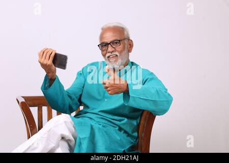 Cool bearded indian old man using mobile phone Stock Photo