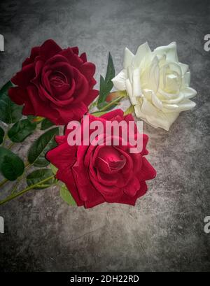 Artificial flowers: three roses on a dark background Stock Photo