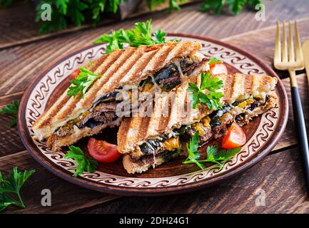 Grilled club sandwich panini with beaf, tomato, cheese and leaf mustard. Delicious breakfast or snack. Stock Photo