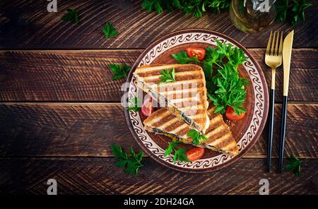 Grilled club sandwich panini with beaf, tomato, cheese and leaf mustard. Delicious breakfast or snack. Top view, copy space, overhead Stock Photo