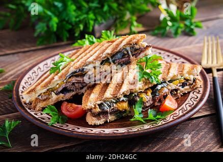 Grilled club sandwich panini with beaf, tomato, cheese and leaf mustard. Delicious breakfast or snack. Stock Photo