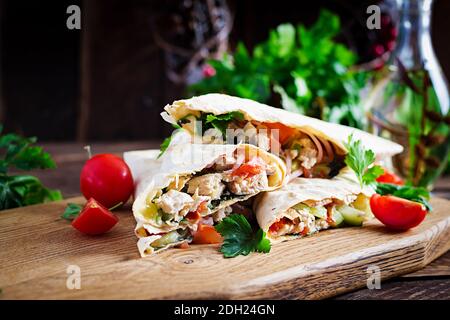 Grilled tortilla wraps with chicken and fresh vegetables on wooden board. Chicken burrito. Mexican food. Healthy food concept. Mexican cuisine Stock Photo