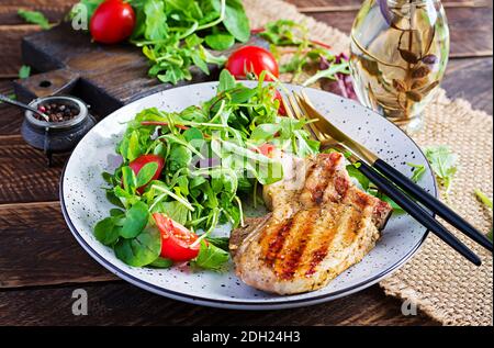 Juicy grilled pork steak with herbs on bone on wooden background. Stock Photo