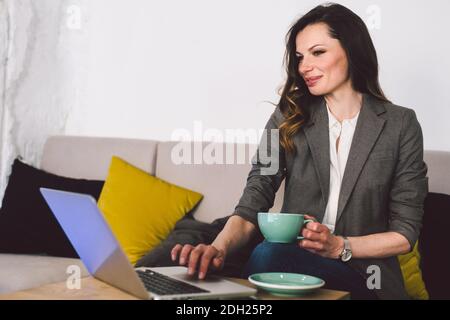 Cheerful skilled middle aged life or business coach enjoying creative process of making new text, sitting at workspace, writing Stock Photo