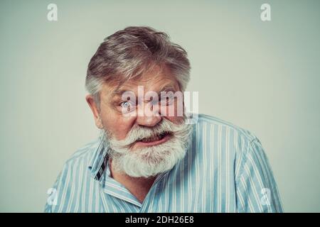Funny senior man posing in a  photoshooting. Happy hipster doing funny expressions. Concept about people and lifestyle. Stock Photo
