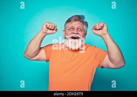 Funny senior man posing in a  photoshooting. Happy hipster doing funny expressions. Concept about people and lifestyle. Stock Photo