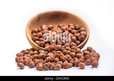 Hazelnuts spilled from wooden bowl on white background. Solid ripe Hazelnuts Stock Photo