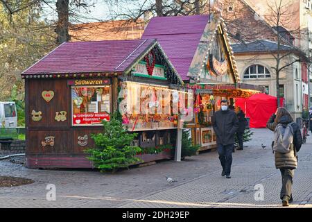 Heidelberg, Germany - December 2020: Festive decorated Christmas market sales booth selling food and drinks with people in face masks walking by Stock Photo